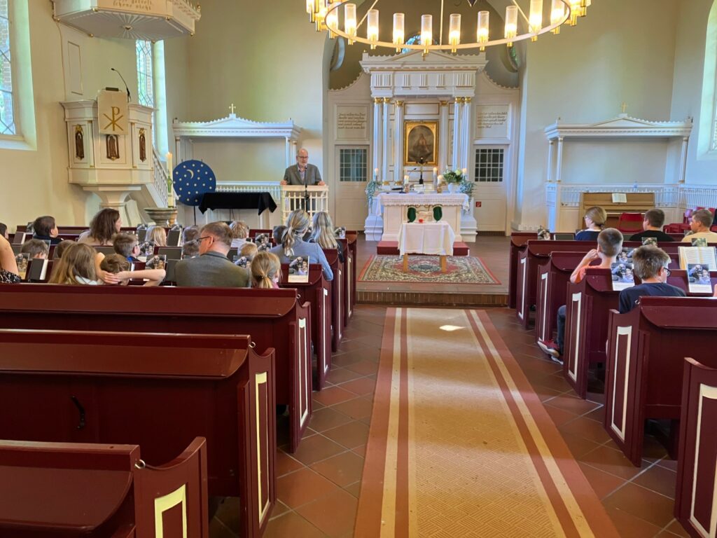 Die Johann-Heinrich-Leiner-Schule besucht mit mehreren Klassen am 15. Mai 2024 Pastor Schoon in der Johann-Heinrich-Leiner-Kirche in Mittegroßefehn.